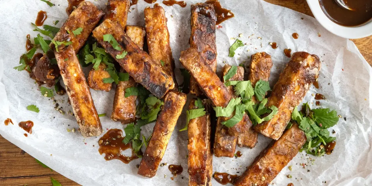Marinierter Tofu, knusprig gebraten und mit einer dunklen Sauce beträufelt, garniert mit frischem Koriander. Perfekt zum Dippen!