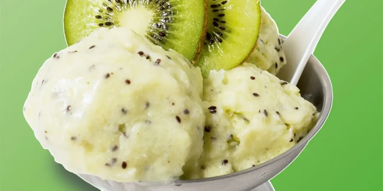 Erfrischendes Kiwi-Eis in einer Schale, garniert mit frischen Kiwischeiben. Ein Löffel steckt darin, bereit zum Genuss.