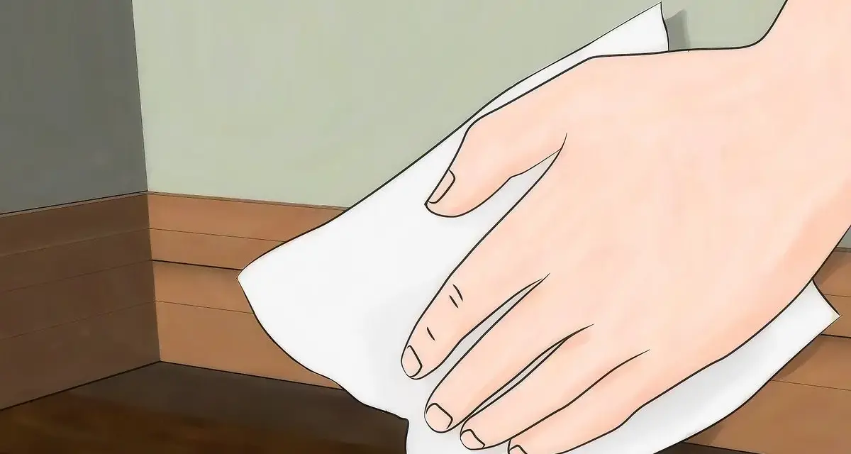 Mano limpiando rodapiés de pintura con un paño blanco.