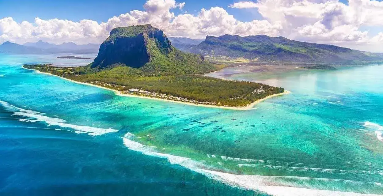 Mauritius pogoda październik: turkusowa woda, zielona góra Le Morne Brabant i białe chmury. Idealna pogoda na rajskie wakacje.