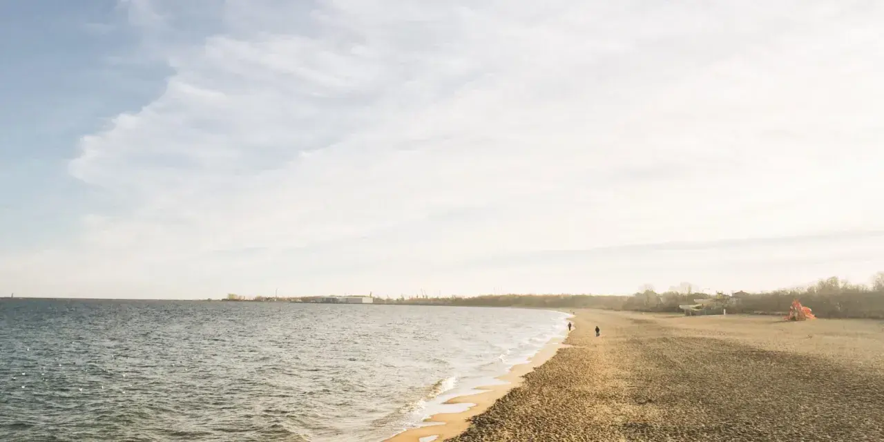 Spokojny dzień nad morzem na Kaszubach. Pusta plaża, delikatne fale i kilka osób spacerujących brzegiem.