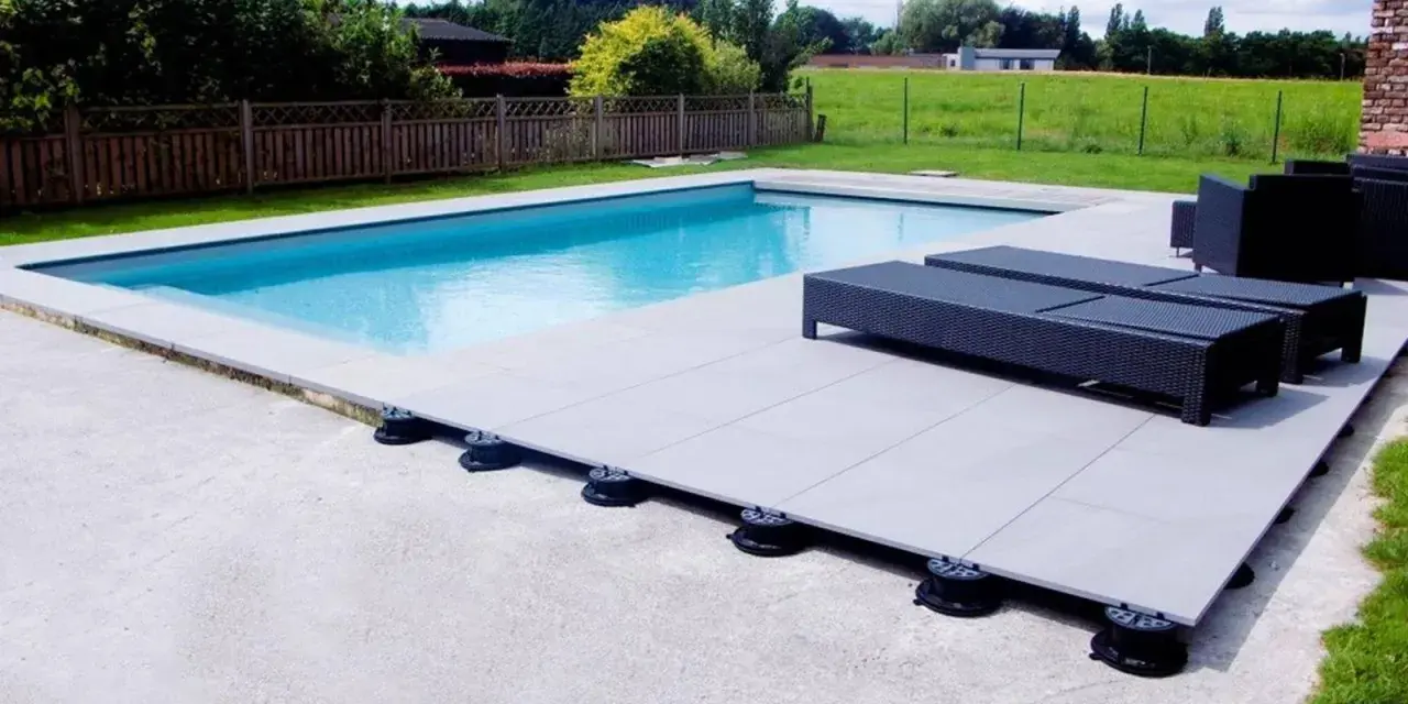 Terrasse de piscine avec dalles sur plots réglables. Le prix au m2 pour ce type de pose est compétitif pour un rendu moderne et pratique.