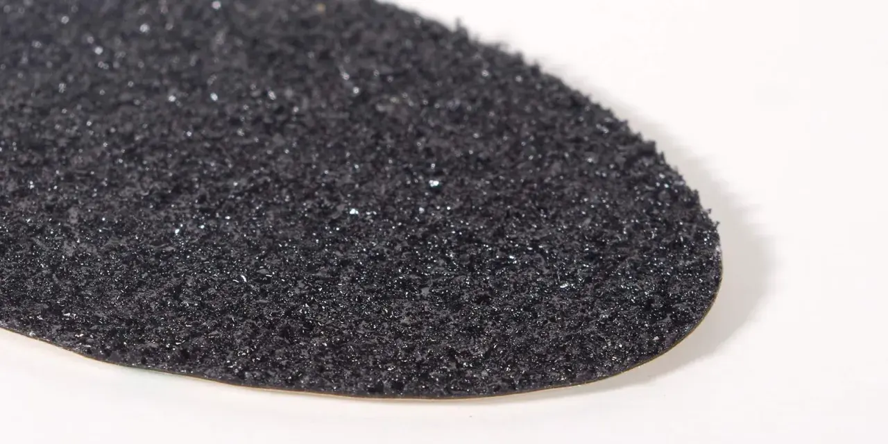 Textura granulada de una suela de caucho resbala, con pequeños brillos que capturan la luz.
