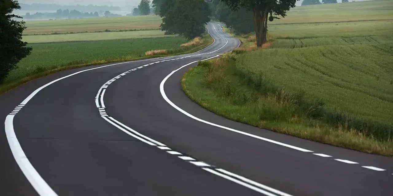 Zakręt drogi z podwójną ciągłą linią. Uważaj, bo wyprzedzanie na podwójnej ciągłej grozi mandatem.