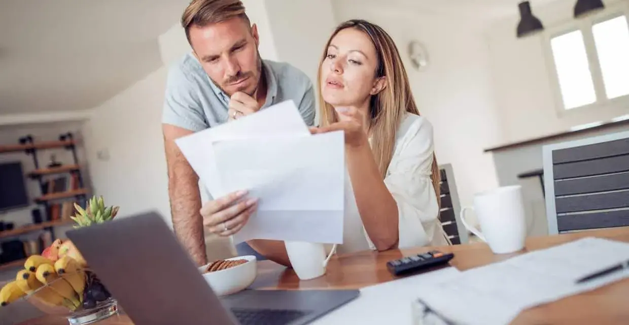 Couple discutent de documents, peut-être une pacs déclaration séparée, devant un ordinateur portable.