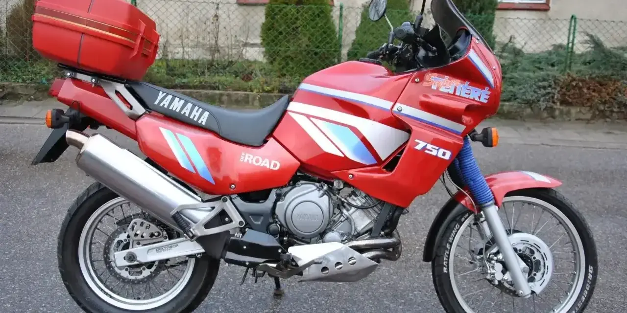 Czerwony motocykl Yamaha XTZ 750 Super Tenere, gotowy na przygodę. Dane techniczne tego modelu są imponujące.