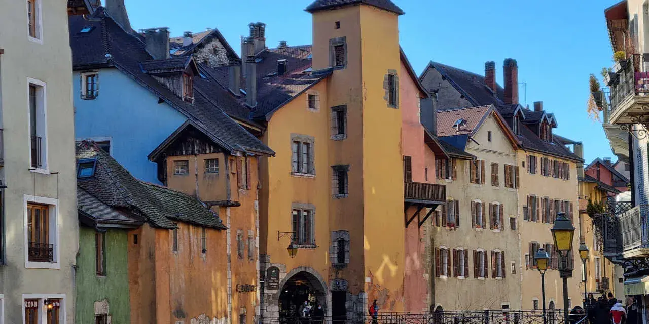 Magnifique journée pour visiter Annecy à pied. Les maisons colorées bordent le canal, un pont de pierre relie les rives.