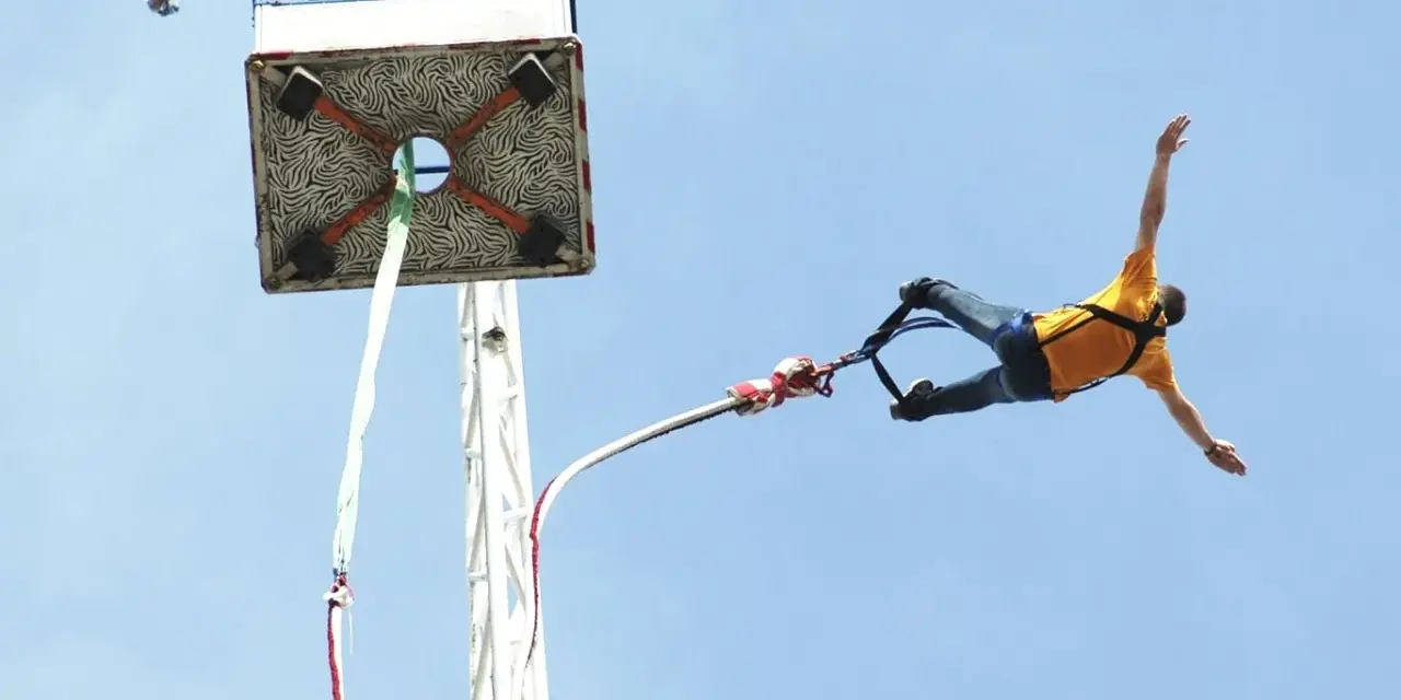 Mężczyzna w żółtej koszulce skacze na bungee. Zastanawiasz się, ile kosztuje skok na bungee?