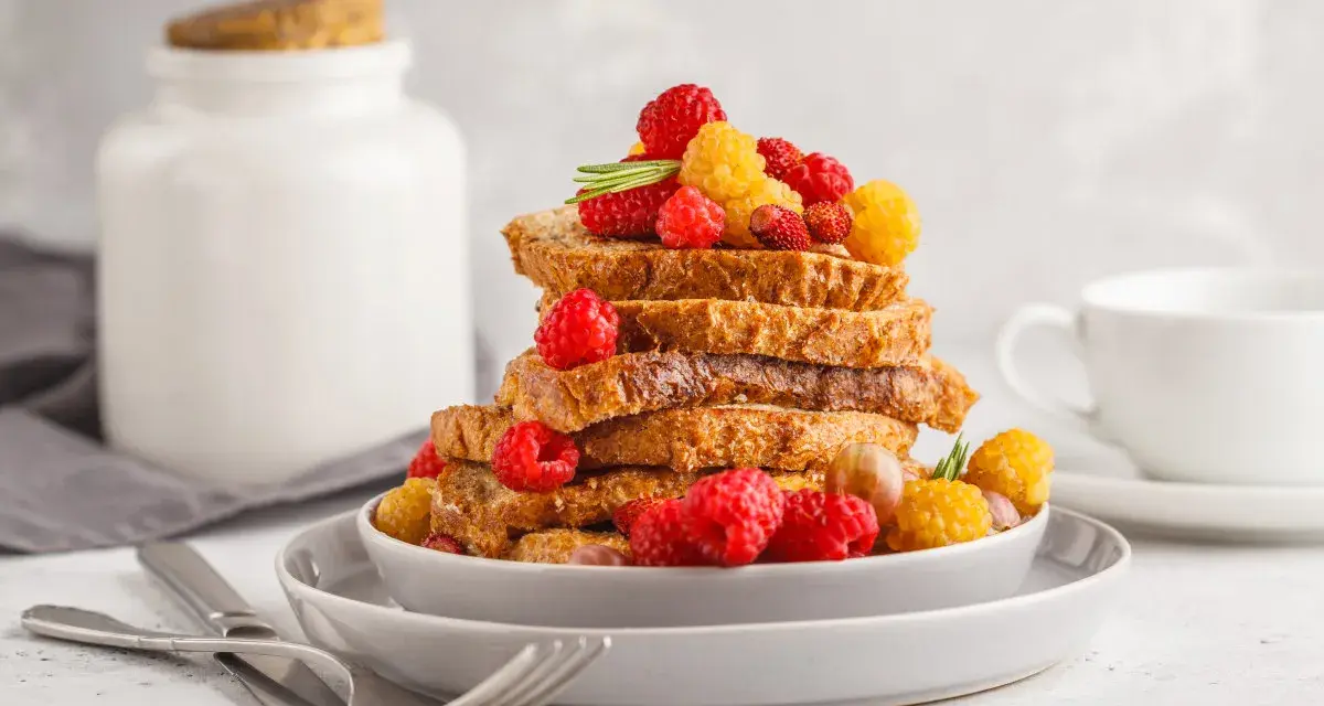 Gestapelte Scheiben Brot, garniert mit Himbeeren und gelben Beeren, perfekt zum Backen mit Hafermilch.
