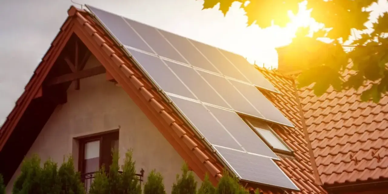 Panele słoneczne na dachu domu. To przykład, jak działa prosument, produkując własną energię.
