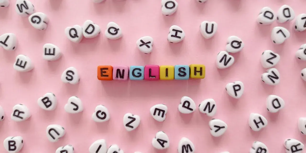 Kolorowe koraliki z literami tworzą napis "ENGLISH" na różowym tle.