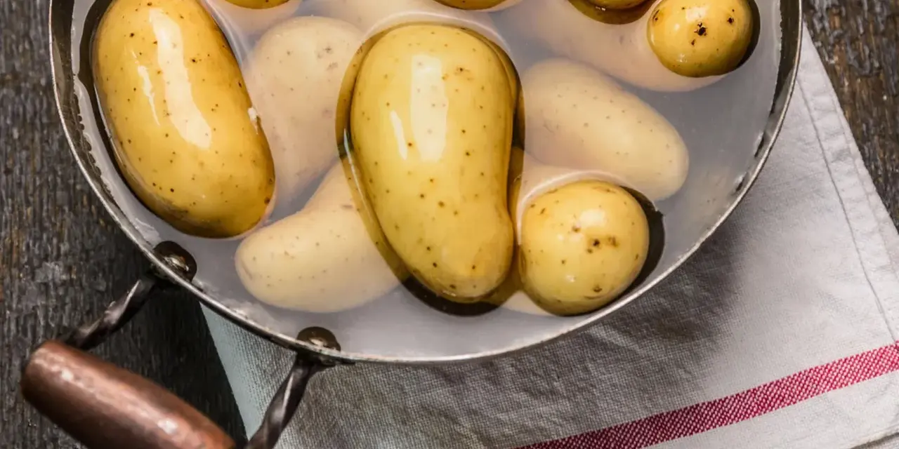 Kleine, gelbe Kartoffeln liegen in Wasser in einem Topf. Sie sind bereit, um sie zu kochen.