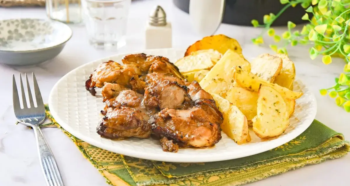 Contramuslos de pollo jugosos y dorados con patatas asadas en un plato blanco.