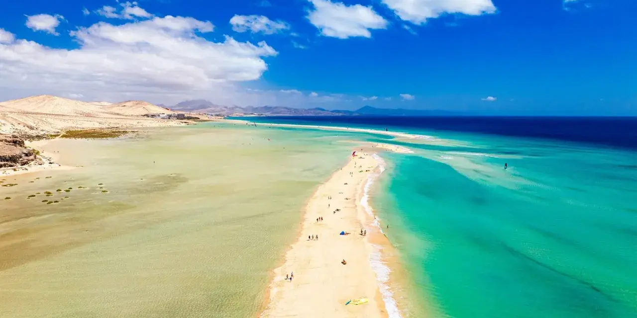 Plaża na Fuerteventurze, z turkusową wodą i piaszczystym cyplem, zachęca do wypoczynku. Czy to Fuerteventura czy Teneryfa, widok zapiera dech.