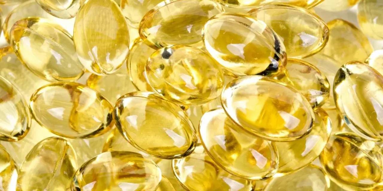 En hög med genomskinliga, gulaktiga kapslar som liknar solens strålar. Dessa kan vara vitaminer som ger energi.