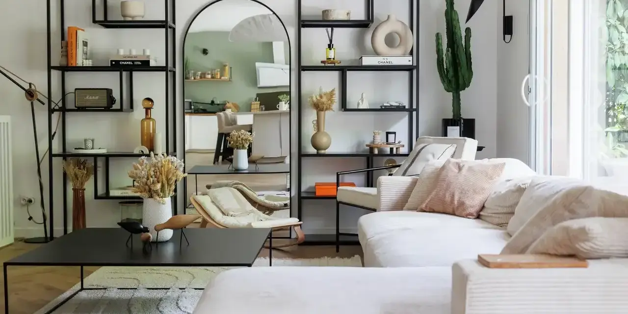 Soggiorno con divano bianco, librerie nere, specchio ad arco e cactus. Un'oasi di pace in stile casa minimal.