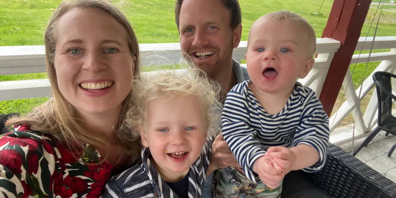Familj med barn på en altan med grönskande landskap i bakgrunden. En härlig stund med norge med barn.