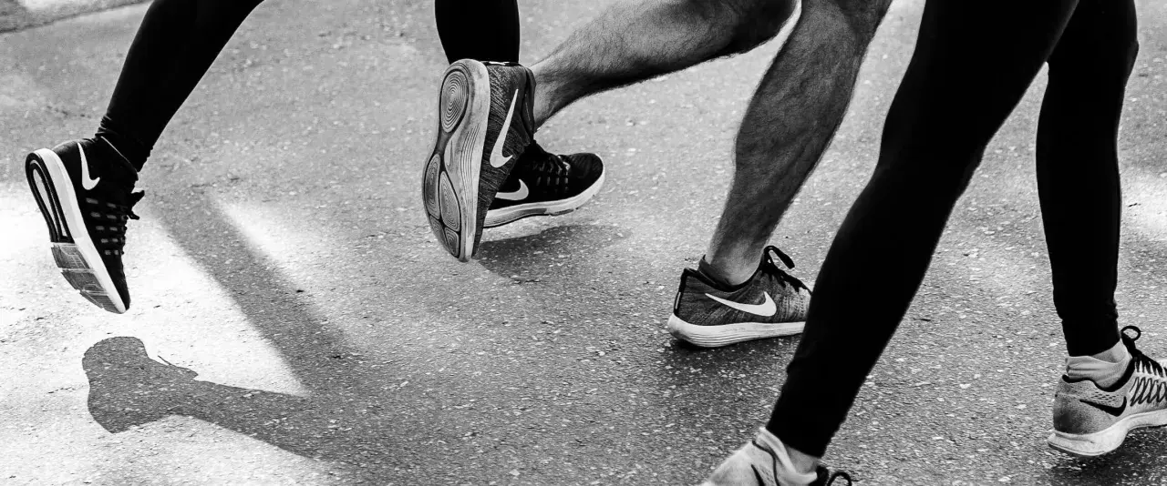 Gambe di corridori in azione, con particolare attenzione al consumo delle scarpe sportive Nike.