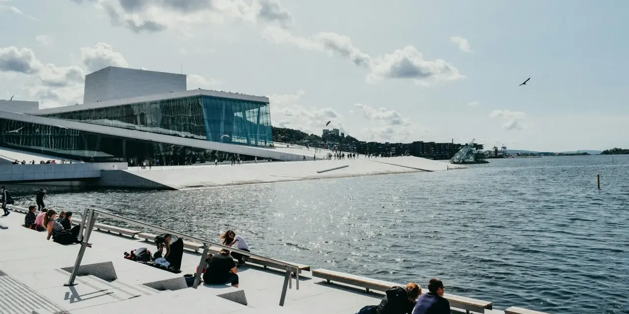 Oslo fiordy jak dojechać: nowoczesna Opera Narodowa i ludzie odpoczywający nad wodą.