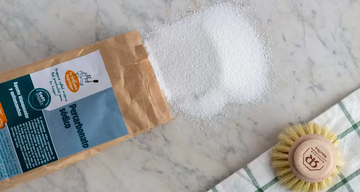 Percarbonato sódico, ideal para ropa color, se derrama de su bolsa junto a un cepillo.
