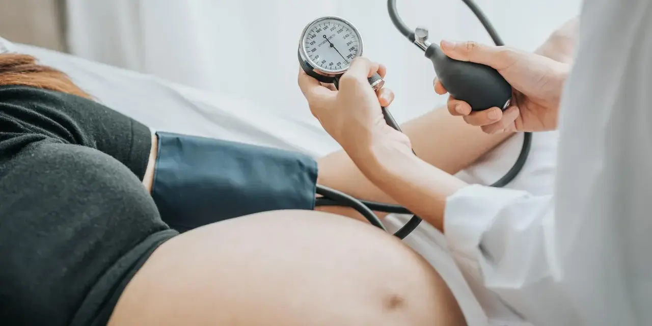 Kobieta w ciąży ma mierzone ciśnienie. Monitorowanie ciśnienia jest kluczowe, by uniknąć powikłań, takich jak wysokie ciśnienie w ciąży.
