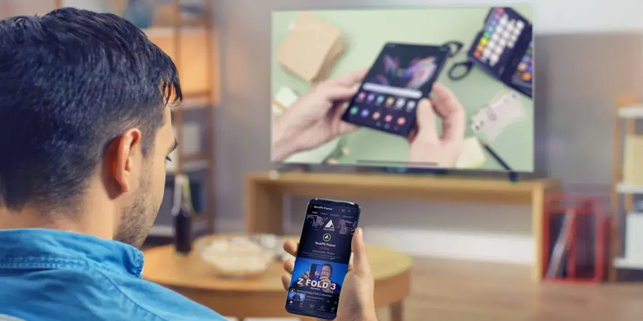 Mann verbindet sein Handy mit dem Fernseher, um ein Video anzusehen. Auf dem Handy ist ein YouTube-Video zu sehen.