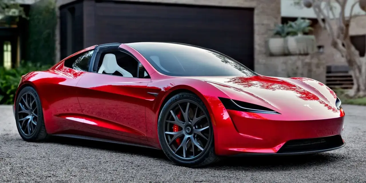 Błyszczący, czerwony Tesla Roadster 2 z białymi siedzeniami stoi przed nowoczesnym domem.