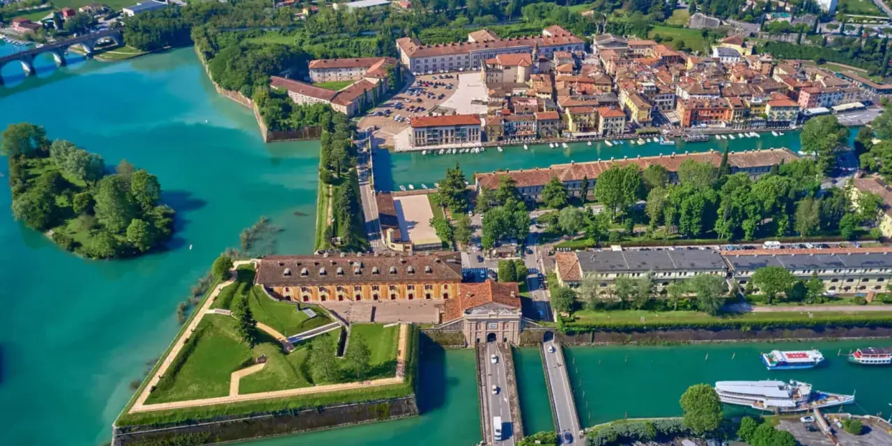 Peschiera del Garda centro storico: fortezza a stella circondata da acque turchesi, con edifici storici e un ponte.