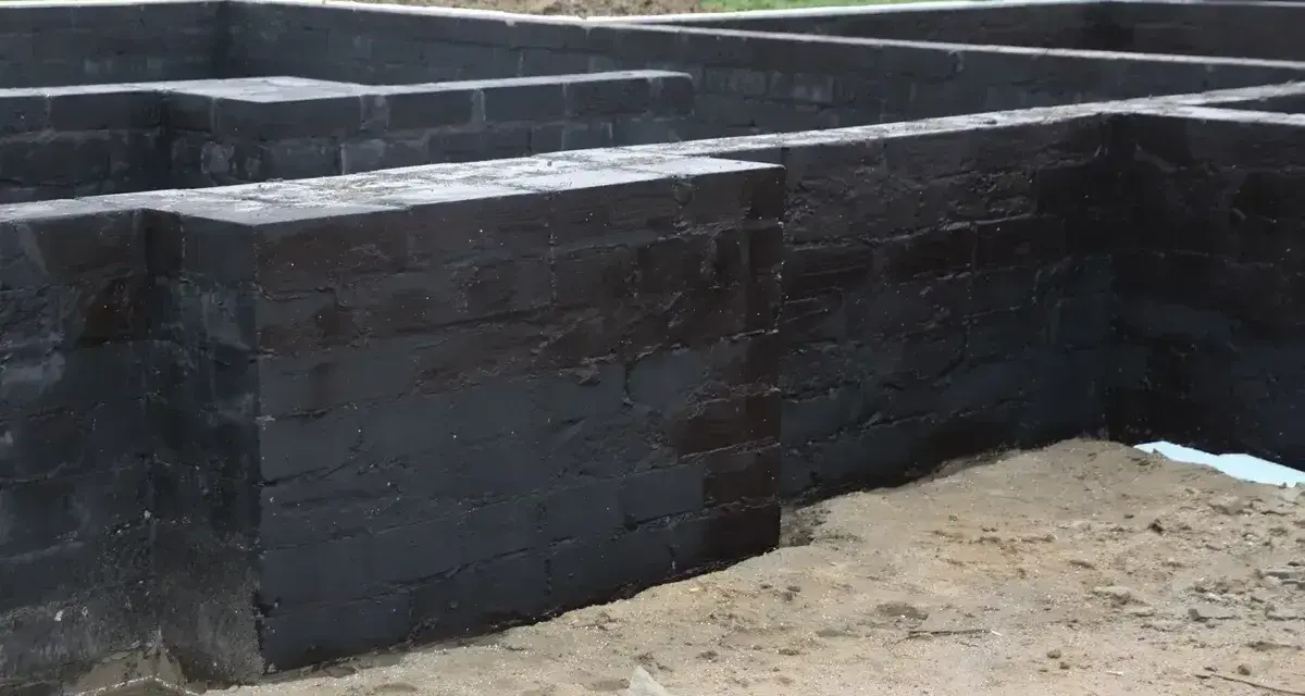 Fundament betonowy z czarnym abizolem, gotowy na kolejne etapy budowy.