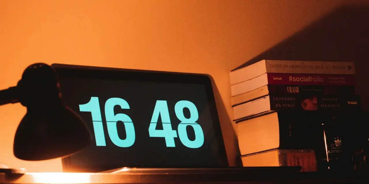 Na ekranie laptopa 16:48. Obok stos książek, w tym "#socialholic". Ile przerwy na 12 godzin pracy?