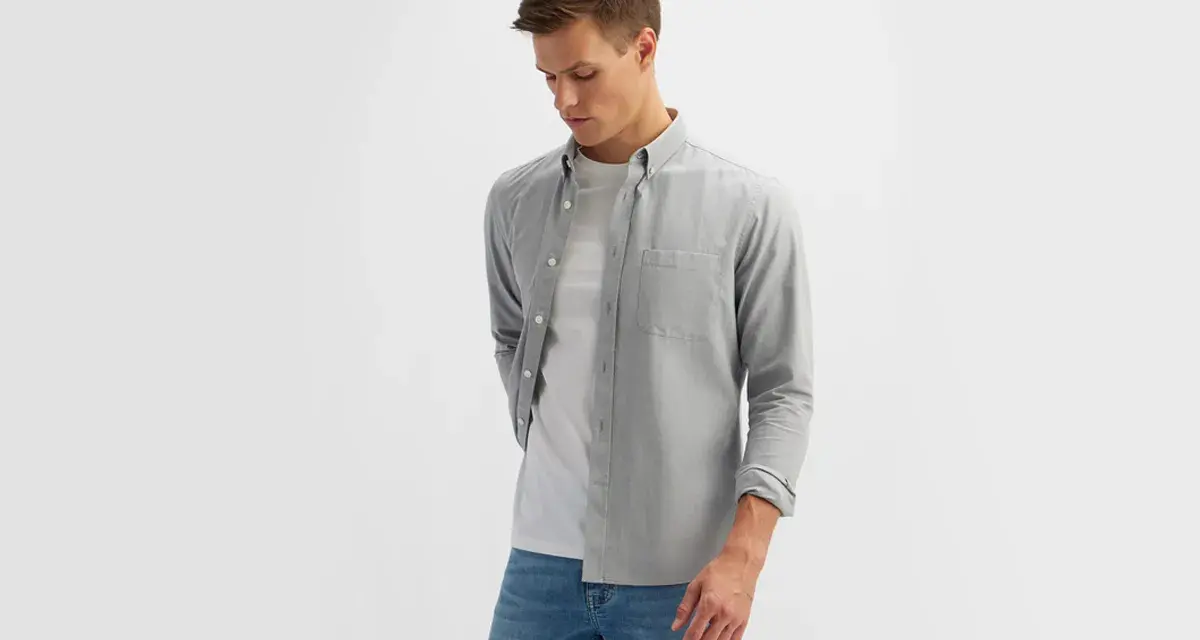 Mężczyzna w szarej koszuli i białej koszulce, prezentujący styl smart casual męski.