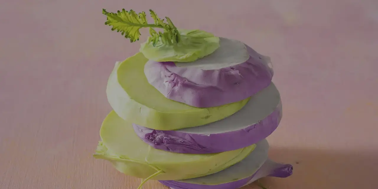 Gestapelte Scheiben von grünem und violettem Kohlrabi, bereit zum Kohlrabi kochen.