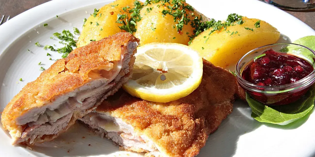 Kotlet po szwajcarsku z ziemniakami, cytryną i żurawiną. Pyszne danie na talerzu.