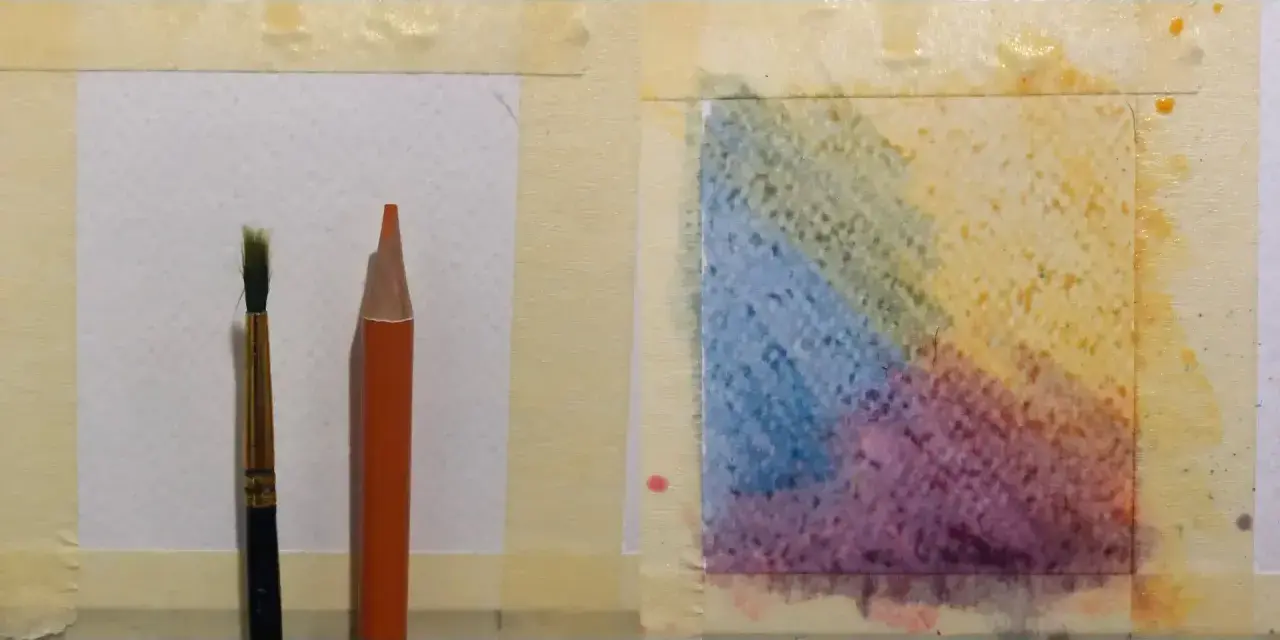 Un pinceau et un crayon aquarelle orange sont prêts pour l'utilisation. Une zone de papier présente des dégradés de couleurs vives.