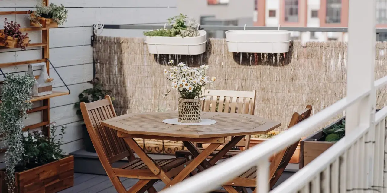 Holztisch mit Stühlen und Gänseblümchen, Wandregal mit Pflanzen, schöne Balkon Ideen für Ihr Zuhause.