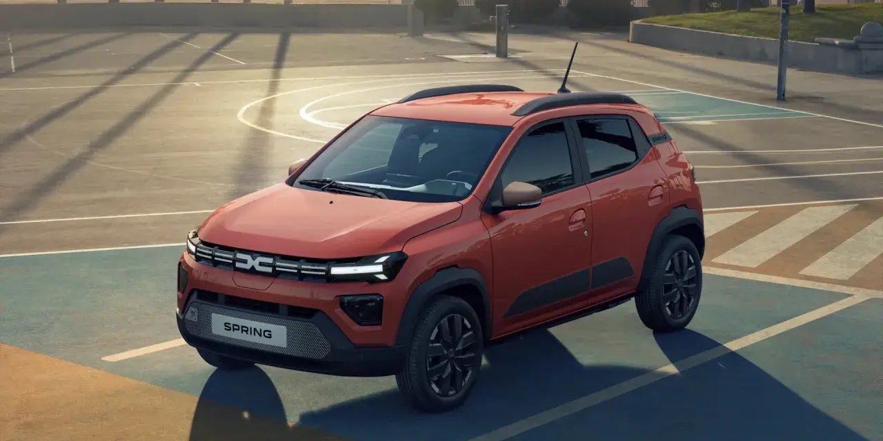 Pomarańczowy Dacia Spring na boisku. Sprawdź atrakcyjną dacia spring cena i odkryj jego możliwości.