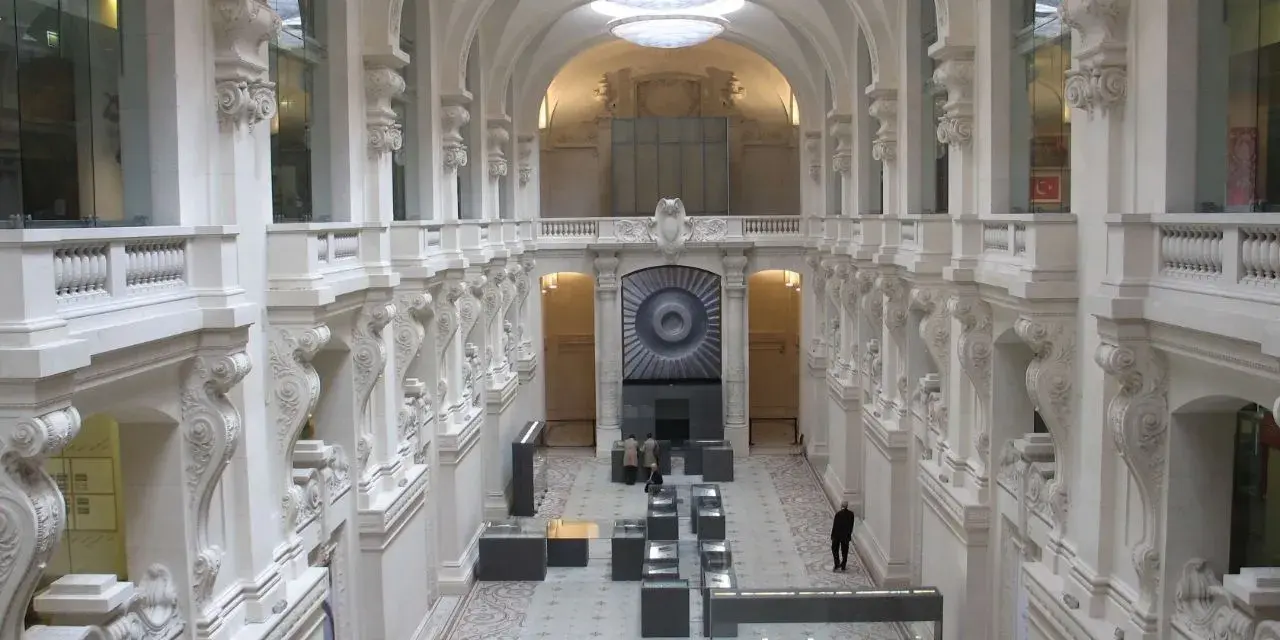 Interior del museo de artes decorativas, con arcos, balcones y vitrinas exhibiendo objetos.