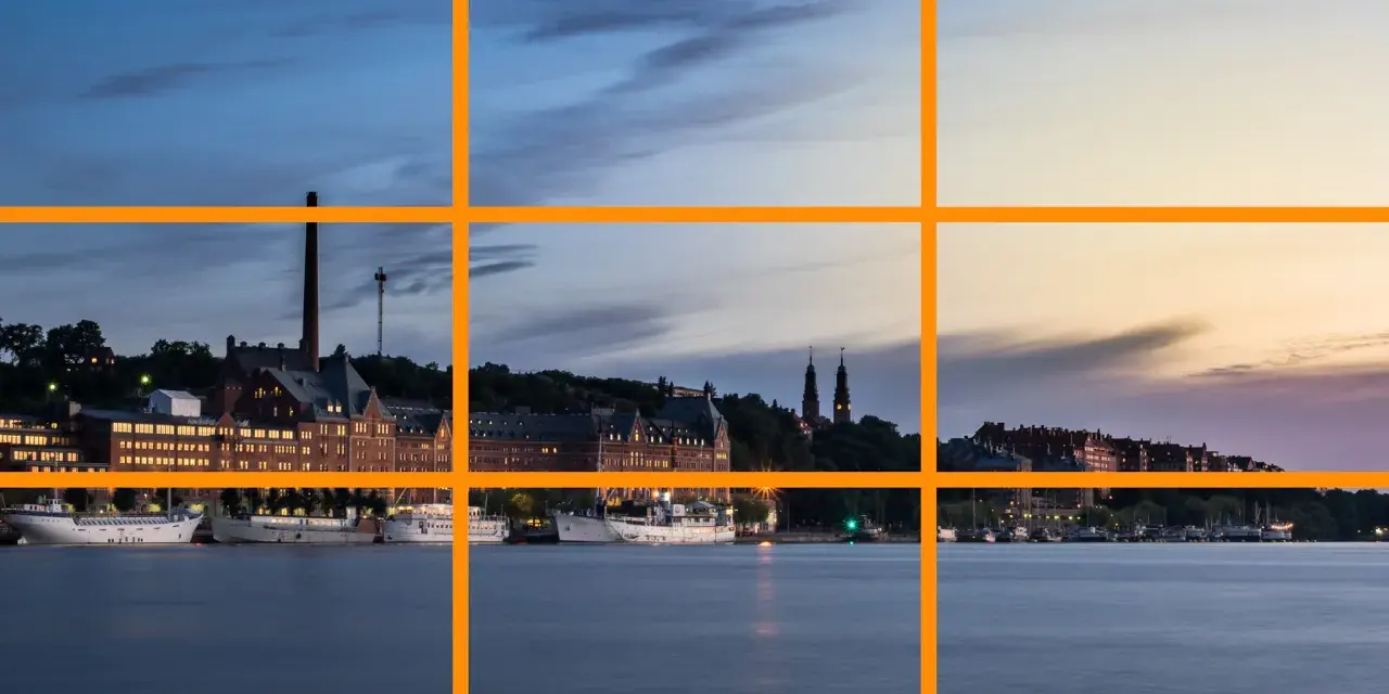 Un paysage urbain au crépuscule, avec des bâtiments historiques et des bateaux le long de l'eau. Un excellent exemple pour un tuto photographie sur la règle des tiers.
