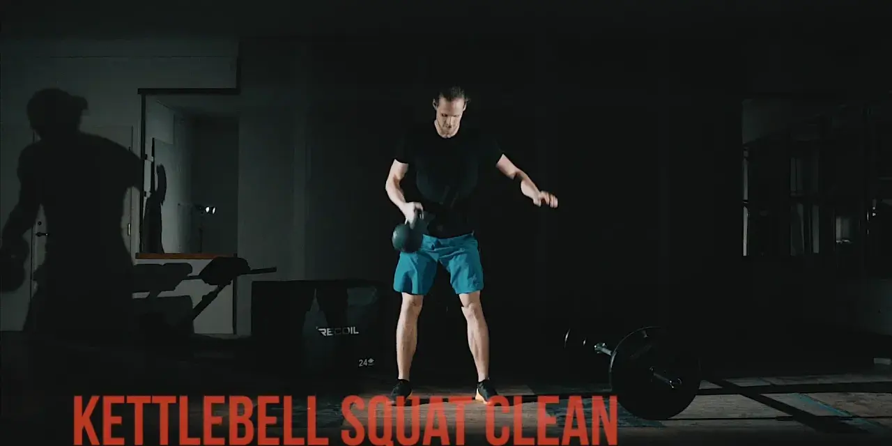 Man utför en kettlebell clean i ett mörkt gym.