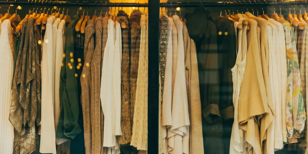 Vetrine di un negozio di abbigliamento con capi in tonalità neutre. Il **store manager** ha scelto un'esposizione elegante.