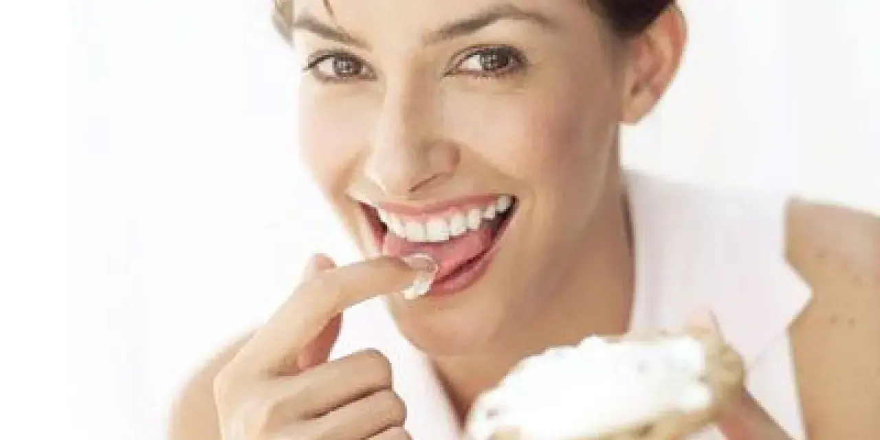 Une femme savoure une bouchée de pain avec de la saint agur crème enceinte, un sourire aux lèvres.