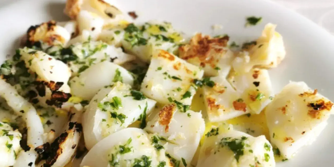 Sabrosa sepia a la plancha, cortada en trozos y aderezada con perejil fresco y aceite de oliva.