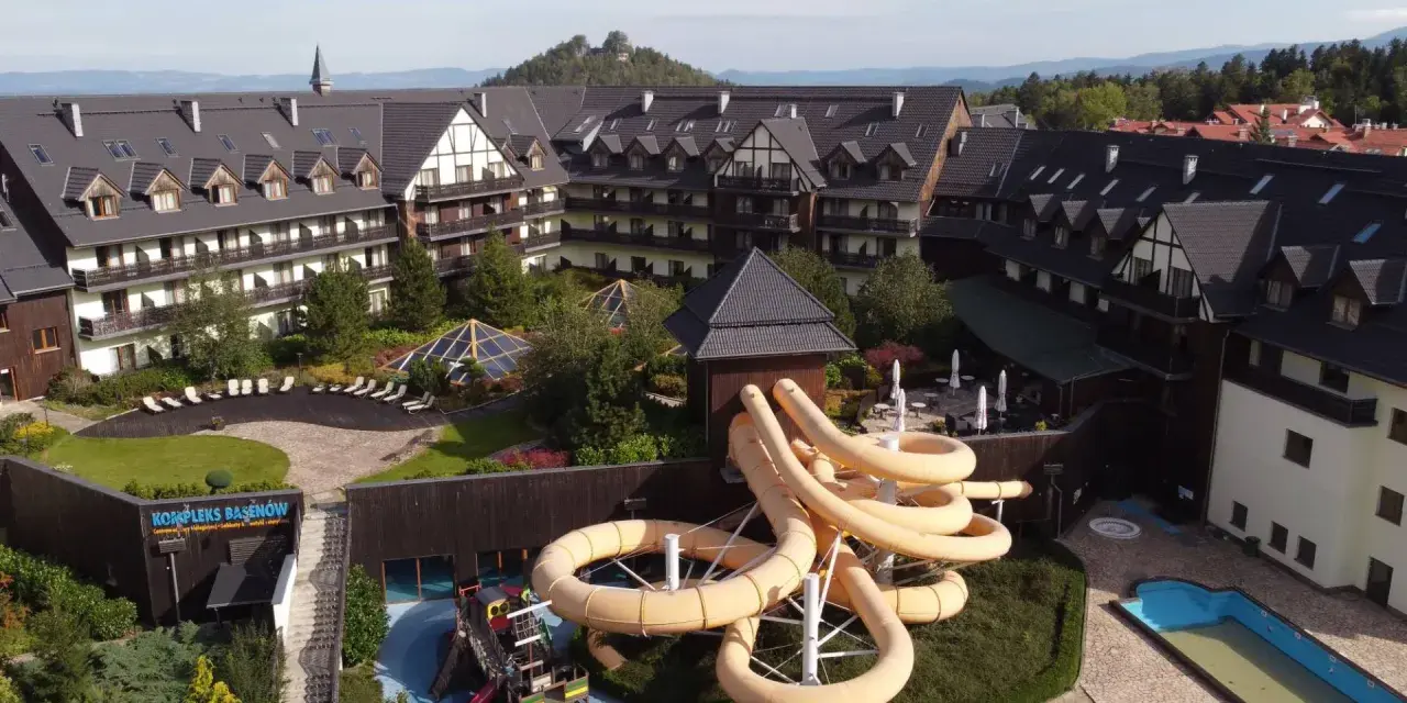 Karpacz hotel z aquaparkiem oferuje zjeżdżalnie i baseny. Widać też góry w tle.