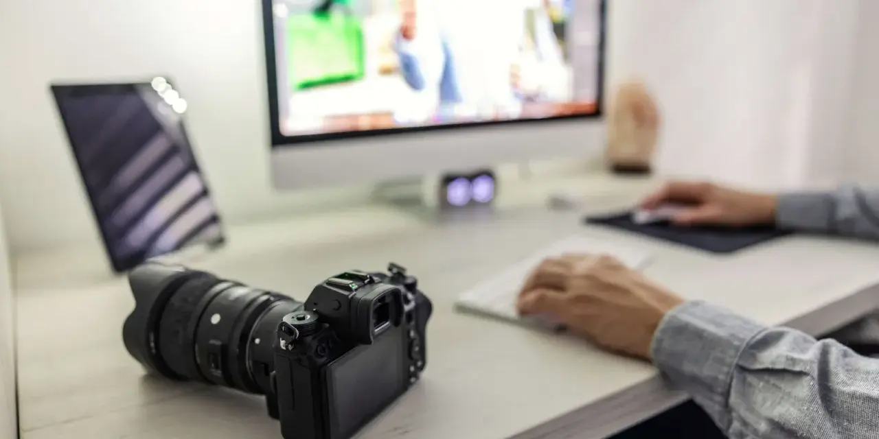 Aparat fotograficzny i tablet na biurku, obok komputera. Ułatwia to proces, jak przegrać zdjęcia z telefonu na komputer.