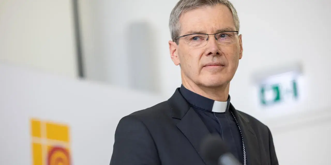 Ein Bischof mit Brille und Soutane spricht in ein Mikrofon. Die Frage "wer bezahlt den Bischof" wird hier nicht beantwortet, aber das Bild zeigt ihn bei einer öffentlichen Rede.