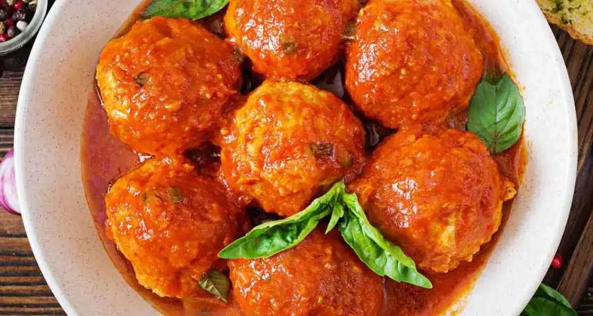 Polpette di pane succulente in salsa di pomodoro, guarnite con foglie di basilico fresco. Un piatto che sa di casa.