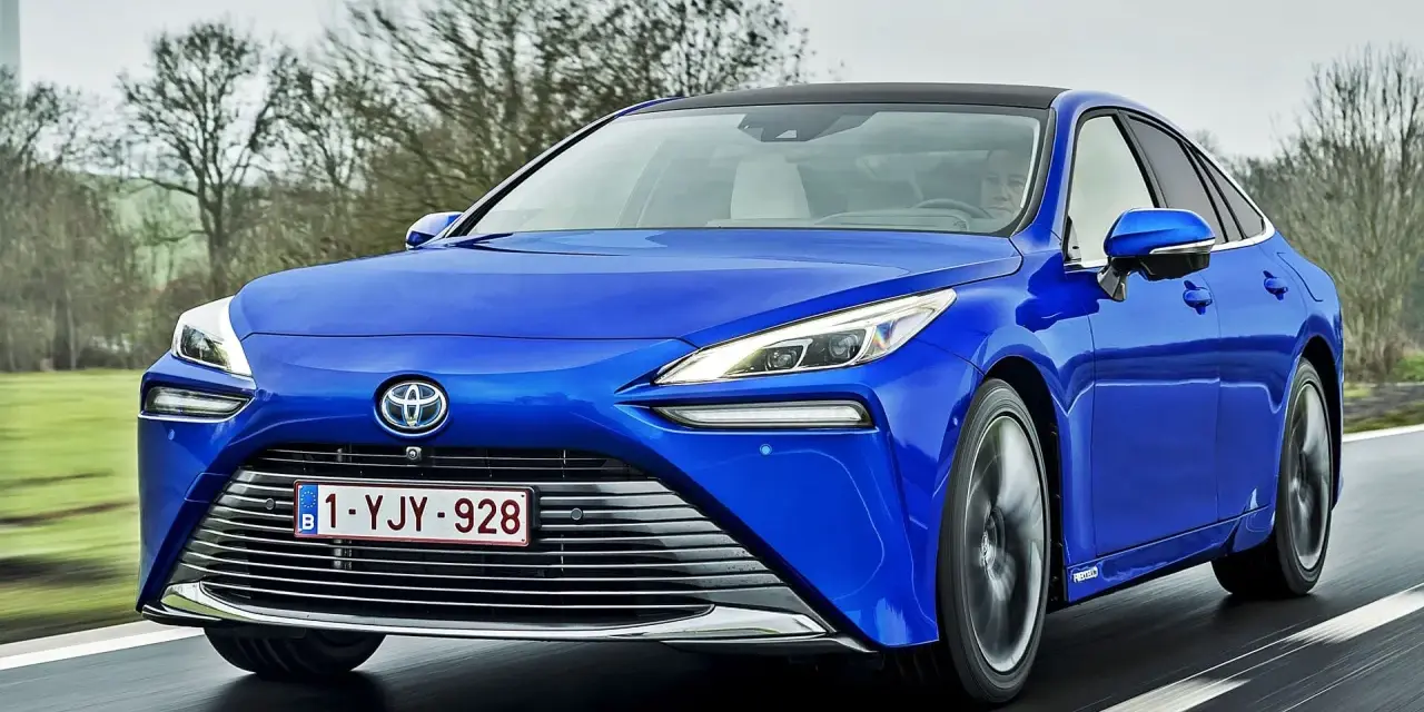 Niebieska Toyota Mirai jedzie po drodze. Sprawdź aktualną toyota mirai cena i dowiedz się więcej o tym innowacyjnym samochodzie.