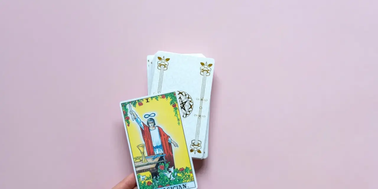 Mano sostiene la carta "El Mago" de un tarot del amor presente pasado y futuro.