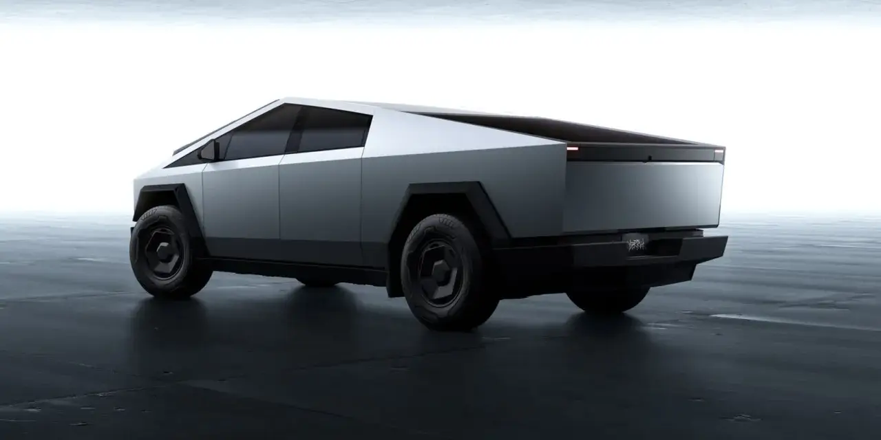 Futurystyczny Tesla Cybertruck w kolorze srebrnym, z ostrymi krawędziami i masywnymi kołami, prezentuje się na ciemnej, betonowej podłodze.