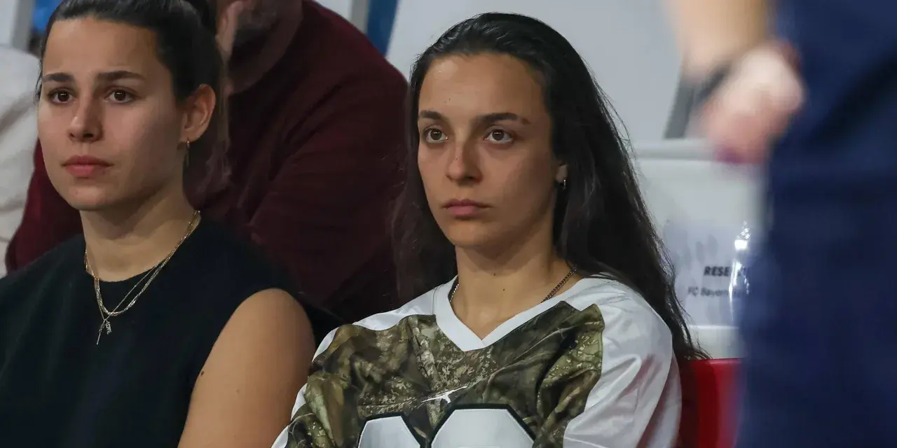 Natalia Padilla Bidas, zamyślona, siedzi na trybunach w koszulce z motywem kamuflażu.